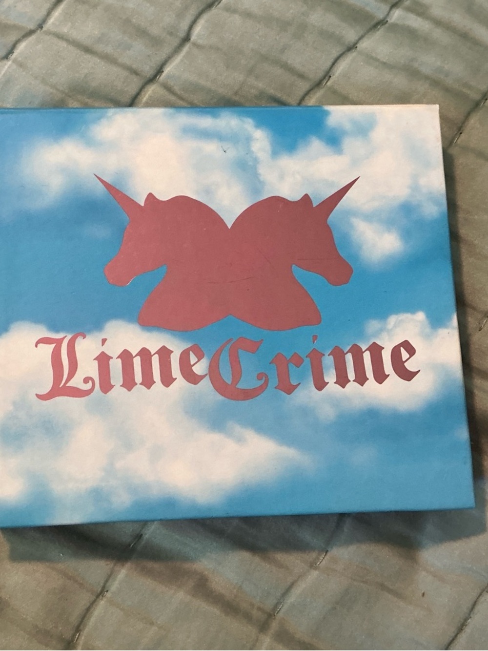 Lime Crime Eyeshadow Palette with Pink Unicorn Logo on Blue Cloud Cover